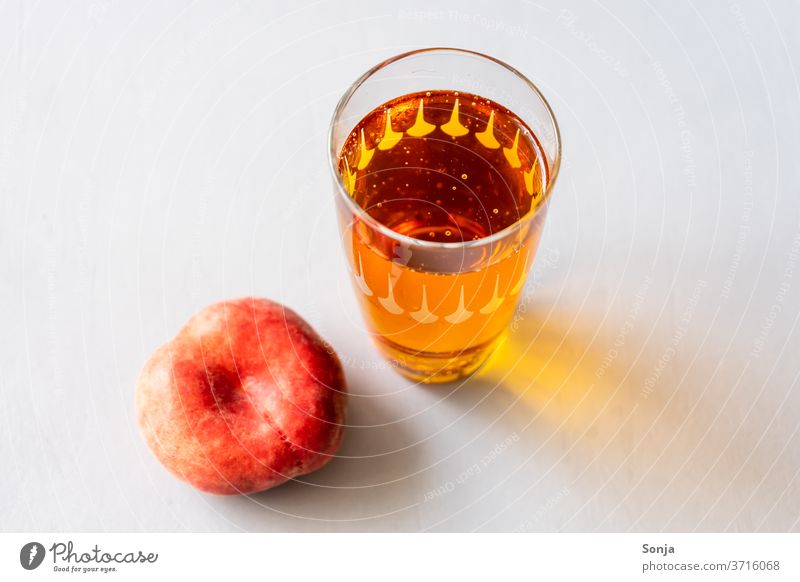 Eistee in einem Glas mit einem frischen Pfirsich auf einem grauen Hintergrund Getränk Sommer Erfrischung Saft süß kalt alkoholfrei Frucht lecker Limonade