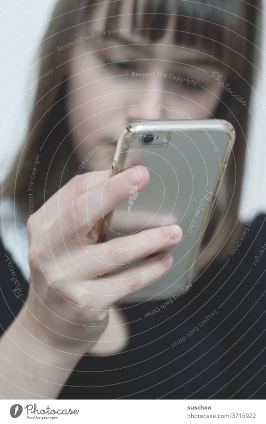 jugendliche schaut auf ihr handy Jugendliche Teenager Hand Finger Handy Smartphone Gesicht unscharf Mädchen Telefon Pubertät Internet jung Junge Frau SMS