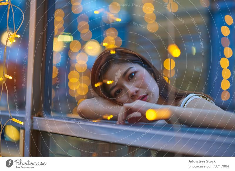 Nachdenkliche Frau im Cafe am Abend Café nachdenklich besinnlich Großstadt Girlande Windstille Wochenende Fenster asiatisch ethnisch fettarm