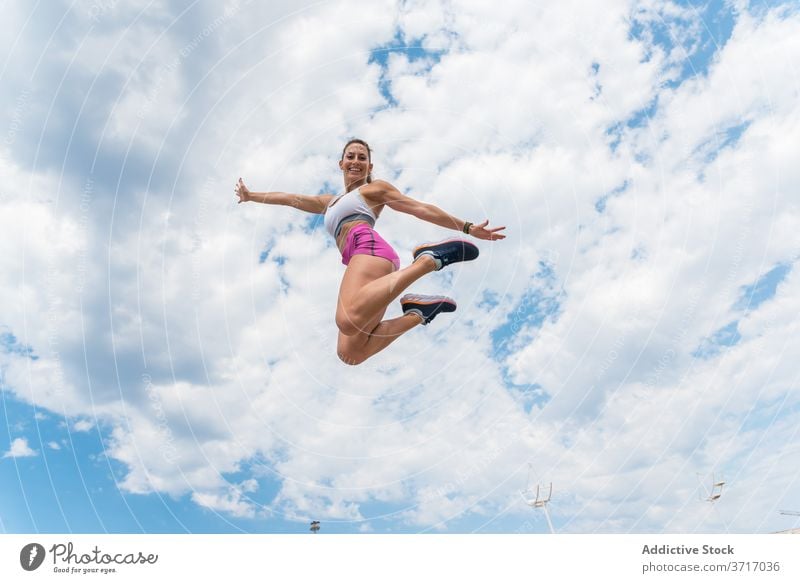 Sportlerin springt beim Training springen beweglich Frau Aktivität intensiv Lächeln Athlet Moment Energie Gesundheit Übung schlank Sportbekleidung über der Erde