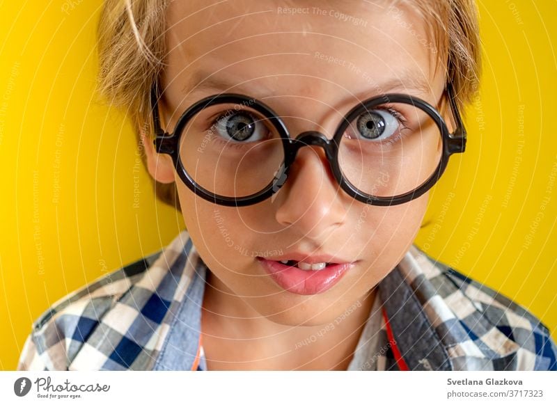 Porträt eines niedlichen und klugen blonden kaukasischen Jungen in einem karierten Hemd auf gelbem Hintergrund. 1. September-Tag. Bildung und zurück zum Schulkonzept. Kinderschüler bereit zu lernen und zu studieren.