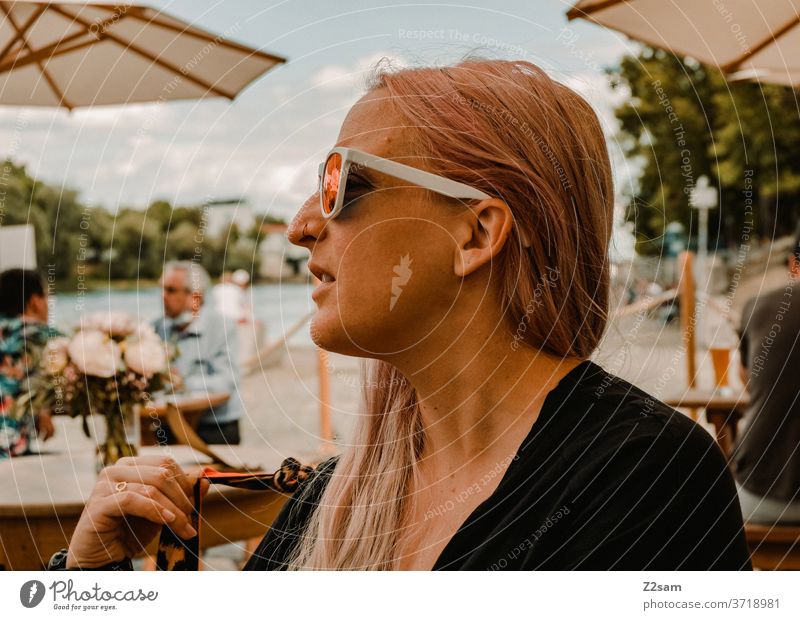 Junge Frau im Restaurant an der Donau donau regensburg restaurant sitzen genießen sommer wärme draußen blond lange haare sonnebrille hübsch schön nachdenklich