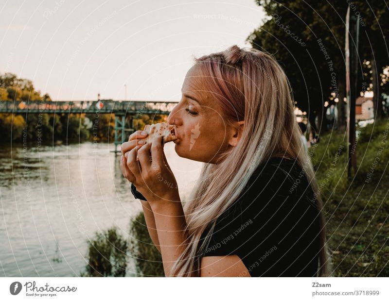 Junge Frau isst Pizza an den Ufern der Donau Essen Lebensmittel Fastfood Hunger Mittagessen Abendessen Ernährung im Freien Bank Regensburg Wasser Sommer Urlaub