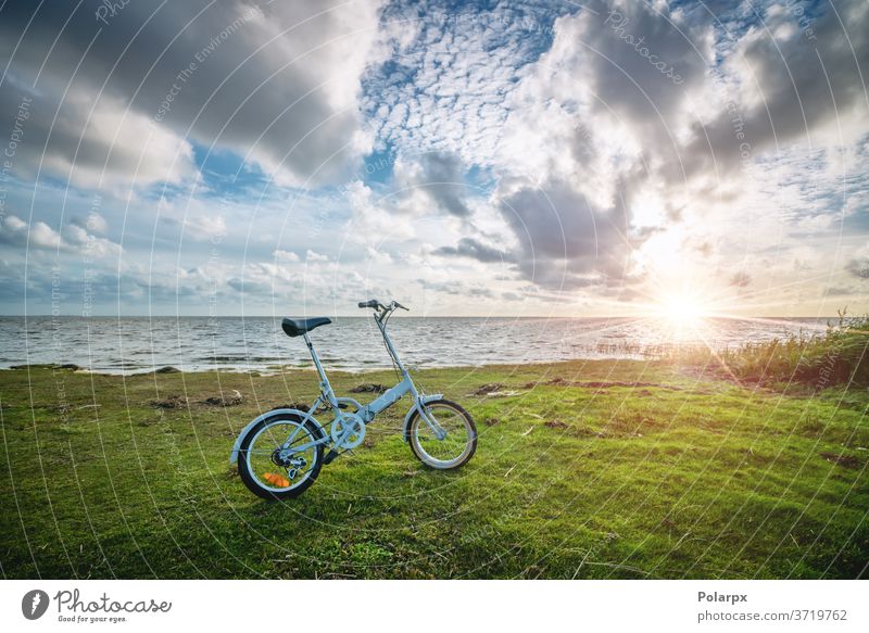 Faltbares Fahrrad am Meer bei Sonnenuntergang sonnig kompakt Sonnenaufgang hell durchstöbern Landschaft Sommer Pedal Fahrradfahren Radfahren im Freien Lifestyle