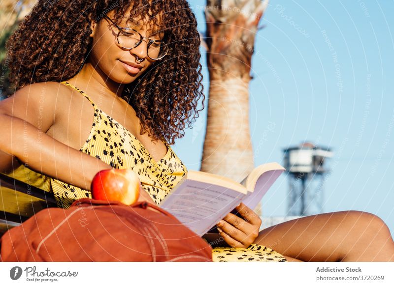 Entspannte ethnische Frau liest Buch im Park lesen Leseratte sich[Akk] entspannen genießen interessant Etage Roman schwarz Afroamerikaner Brille Inhalt