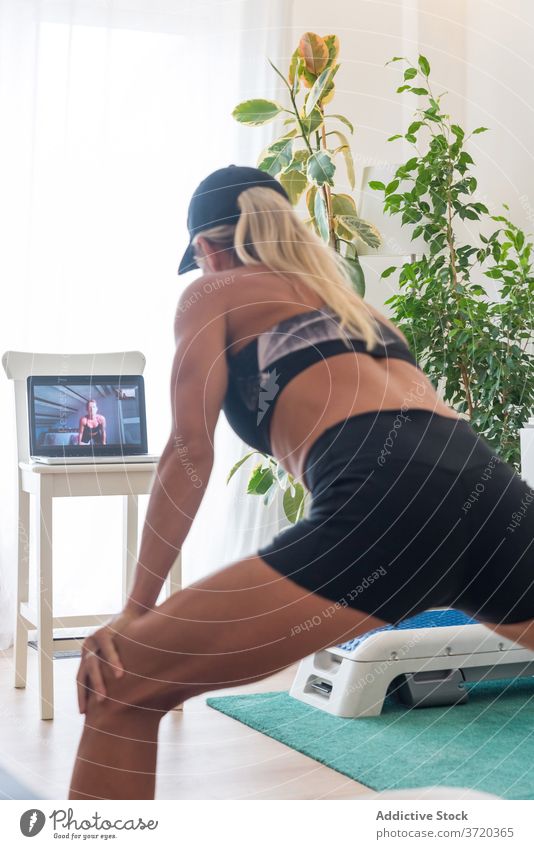 Schlanke Frau macht Übungen zu Hause Seitenlonge heimwärts Training online Video Tutorial zuschauen benutzend Laptop Fitness Apparatur Gerät Internet Sport
