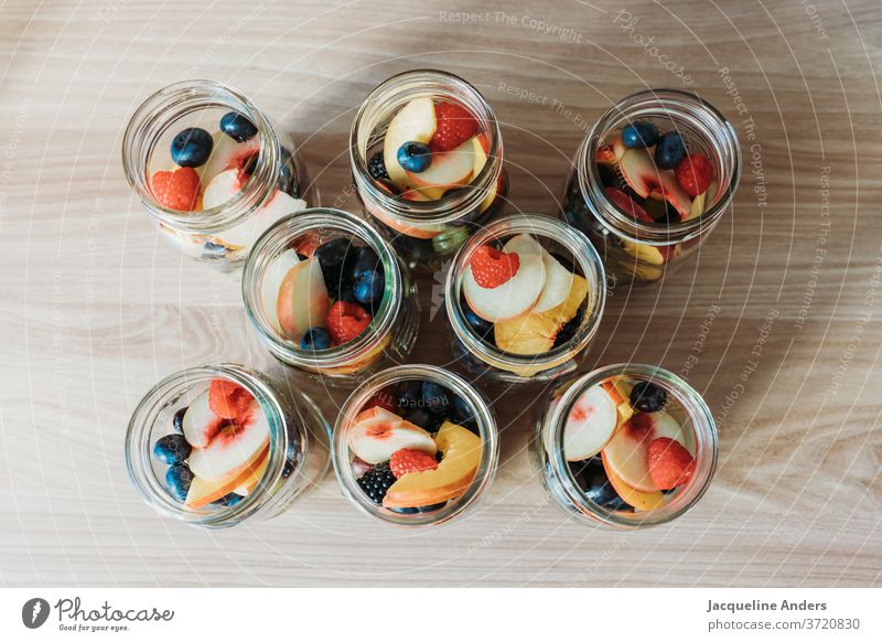 frisches Obst in Gläsern Glas Himbeeren Pfirsich Blaubeeren Heidelbeeren Tisch Küche Nektarine aufgeschnitten Frucht Lebensmittel lecker Ernährung