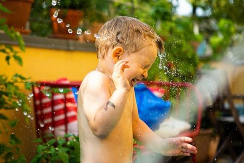 Junge wird auf der Terrasse mit Wasser bespritzt und dreht sich weg platschen spritzen Kind nackt Haut Garten Balkon Planschbecken Garten-Schleife Tropfen