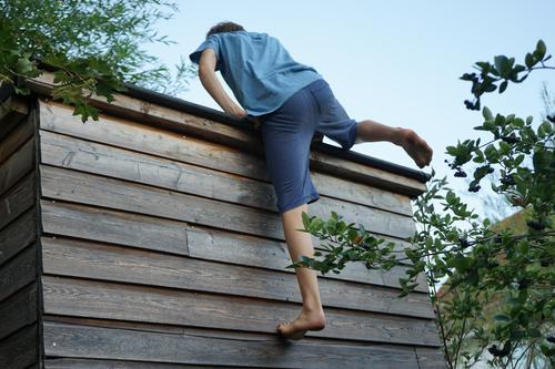 Junge klettert eine Hauswand hoch Kletern Teenager Sommer warm draußen sportlich Sport hoch hinaus hochklettern Freizeit bouldern Kletterübung