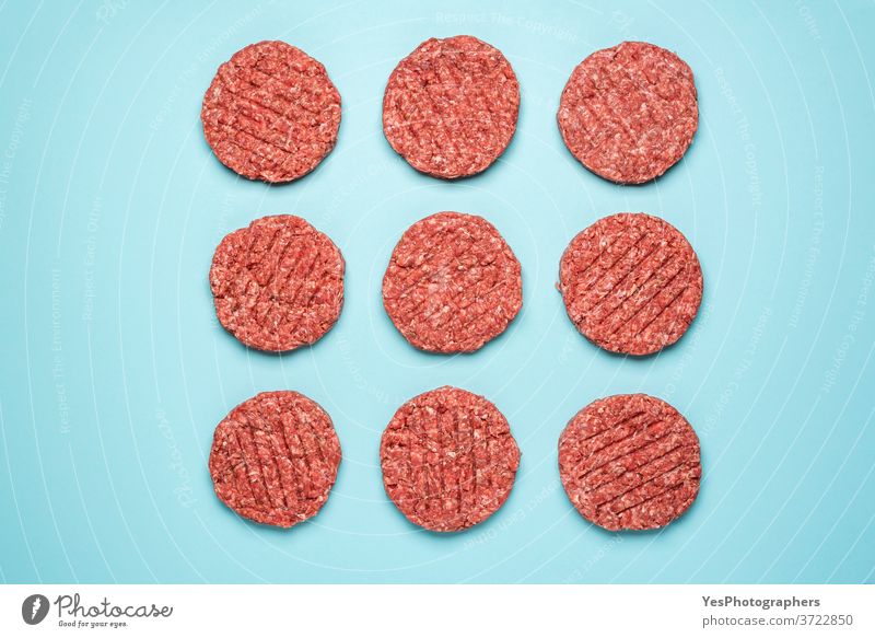 Rohe Hamburger-Frikadellen isoliert auf blauem Hintergrund. Rohes Burgerfleisch von oben gesehen. obere Ansicht ausgerichtet Barbecue grillen Rindfleisch