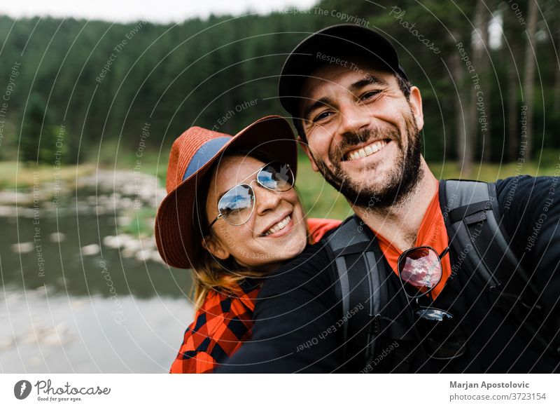 Selfie eines jungen Paares in den Bergen am Fluss 30s aktiv Erwachsener Abenteuer Rucksack Rucksacktouristen Rucksacktourismus Freund Fotokamera lässig