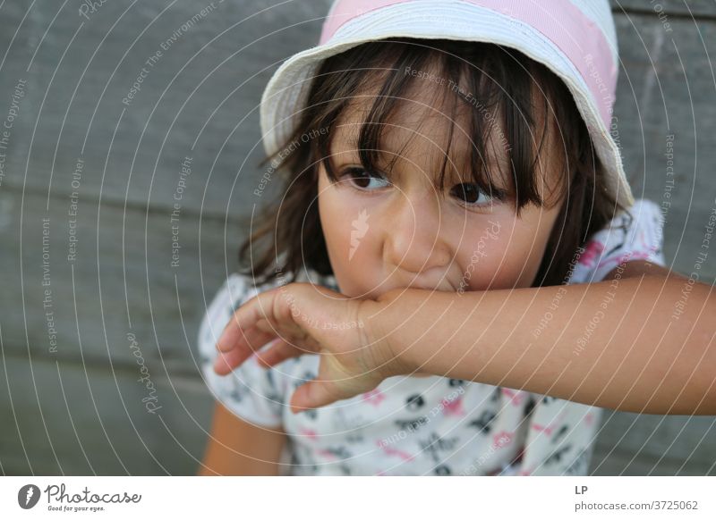 Mädchen mit einem Hut, das die Hand auf dem Mund hält Blick Oberkörper Porträt Hintergrund neutral Nahaufnahme Außenaufnahme Gedeckte Farben Kindheitstraum