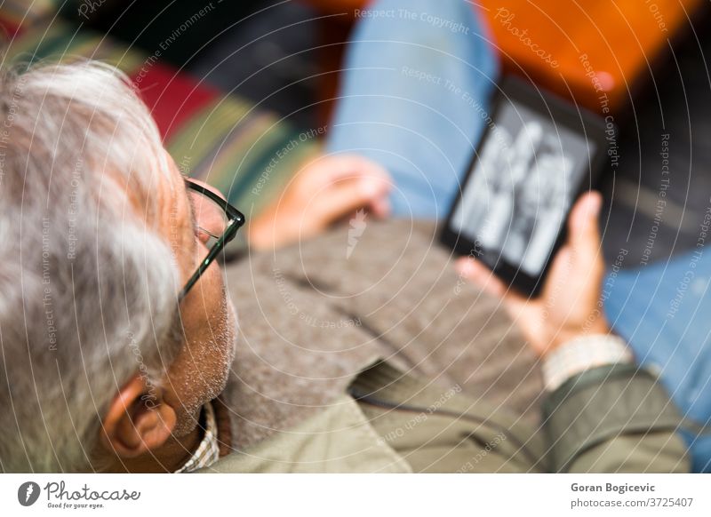 Älterer Mann benutzt ein E-Book-Lesegerät Erwachsener allein Buch Pause Kaukasier Nahaufnahme Gerät digital eBook genießend Senior Hände Halt heimwärts Haus