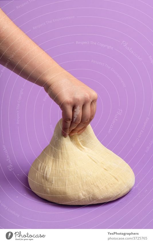 Brotteig isoliert auf violetter Farbe. Frauenhand, die den Teig streckt. Backen zu Hause Hintergrund backen Bäckerei Ball Brötchen Konzept Essen zubereiten