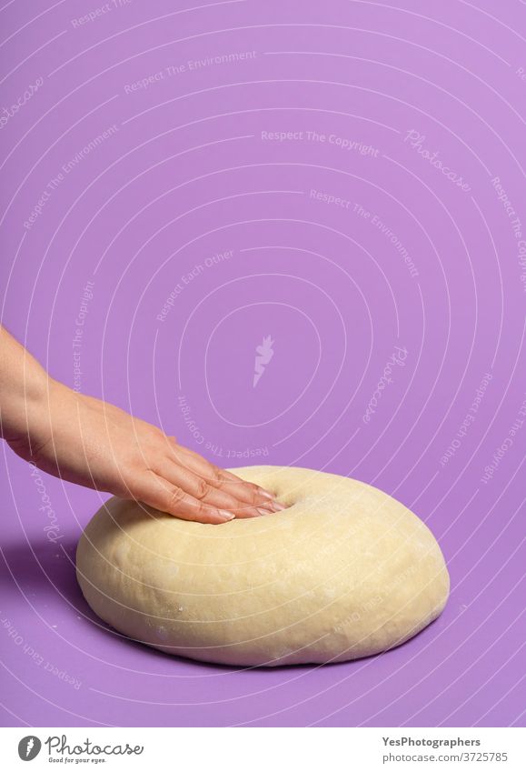 Ungekochter Teig isoliert auf violettem Tisch. Frauenhand drückt den Teig Hintergrund backen Bäckerei Ball Brot Brotteig Brötchen Konzept Essen zubereiten