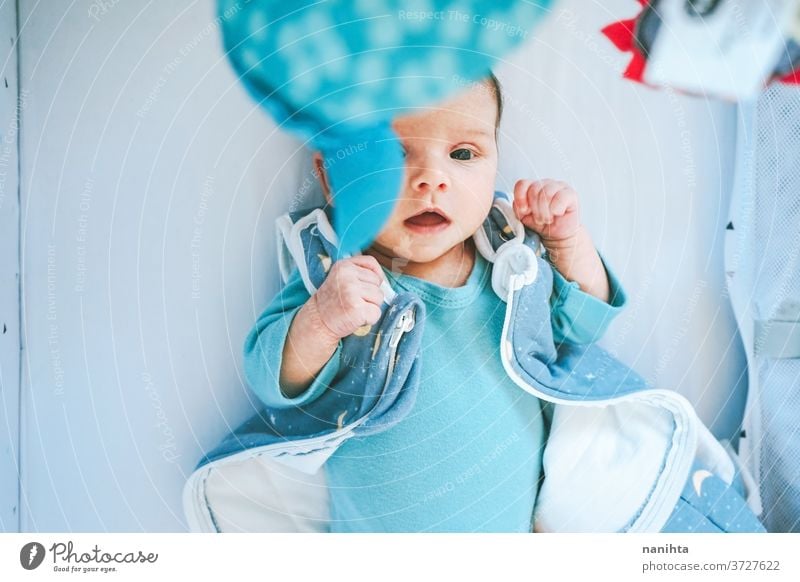 Liebliches und verspieltes Neugeborenes in ihrem Schlafzimmer zu Hause neugeboren spielerisch neugierig Baby lieblich niedlich unisex Kleidung Wiege Babybett