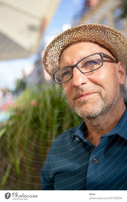 Zuversichtlicher Mann mit Strohhut einzeln Zufriedenheit ruhig Erholung Brillenträger Blick nach oben Dreitagebart optimistisch Außenaufnahme