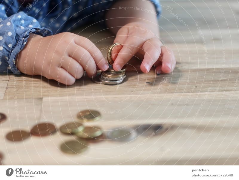 Kind spielt mit Geldmünzen und sortiert sie. Kinderspiel, Neugierde, Taschengeld cent kinderhände kinderspiel finanzen kindergeld famiiengeld armut sortieren