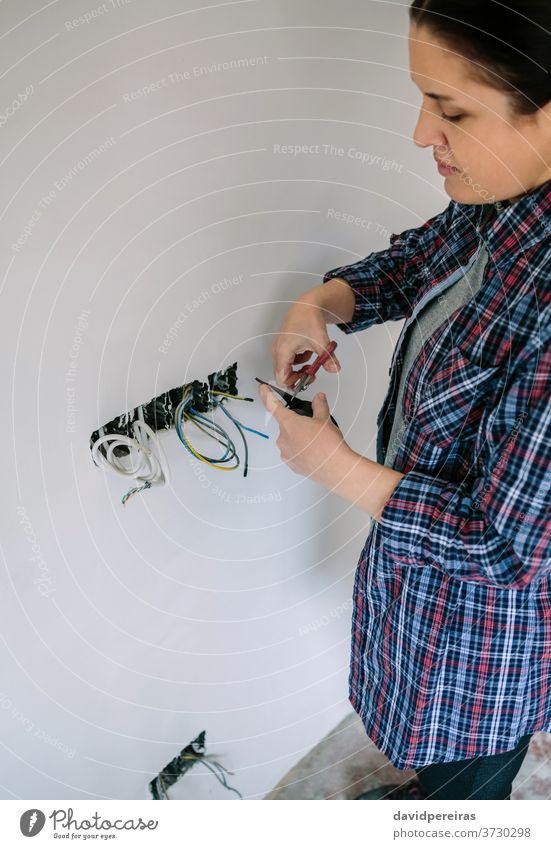 Elektriker, der an der Elektroinstallation eines Hauses arbeitet Elektromonteur Frau Elektrotechniker Installation Schneiden Isolierband schaltet Elektroband
