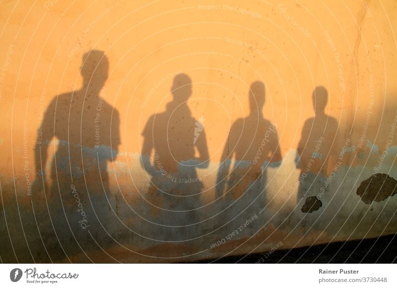 Schatten von vier jungen Männern gegen eine Wand bei Sonnenuntergang Hintergrund Abenddämmerung Freunde Menschengruppe Gruppe von Freunden im Freien Person