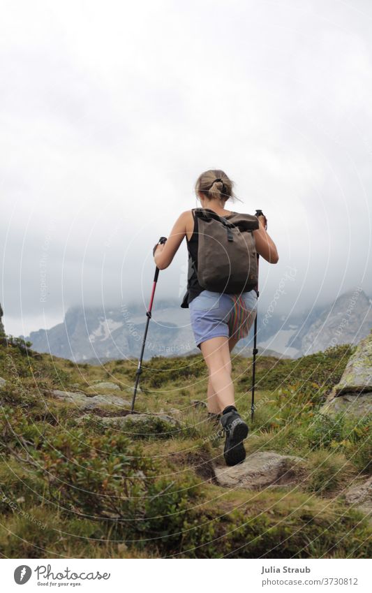 Frau wandert mit Stöcken in den Händen in den Bergen wandern hinten Berge u. Gebirge Gipfel Wanderstöcke Rucksack Rucksackurlaub rucksacktourist Rucksackwandern