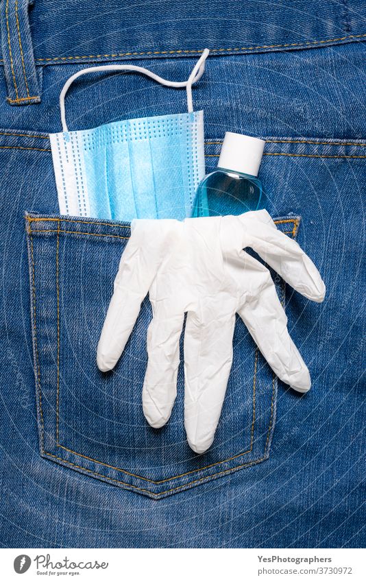 Neue Normalität im Pandemiekonzept. Medizinische Maske, Handdesinfektionsmittel und Handschuhe in der Gesäßtasche der Jeans Vermeidung Hintertasche blau Pflege