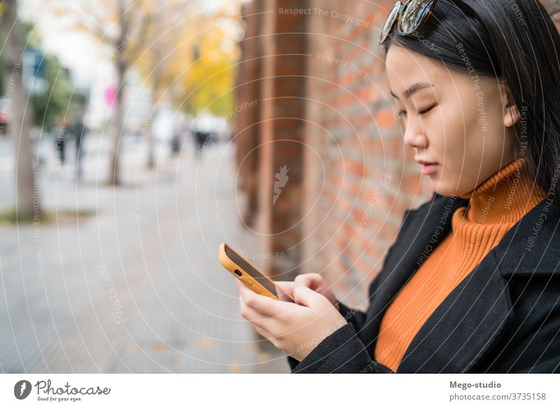 Asiatische Frau, die ihr Mobiltelefon benutzt. Straße Smartphone Telefon asiatisch Mobile Menschen urban klug Funktelefon Text jung SMS Nachricht im Freien