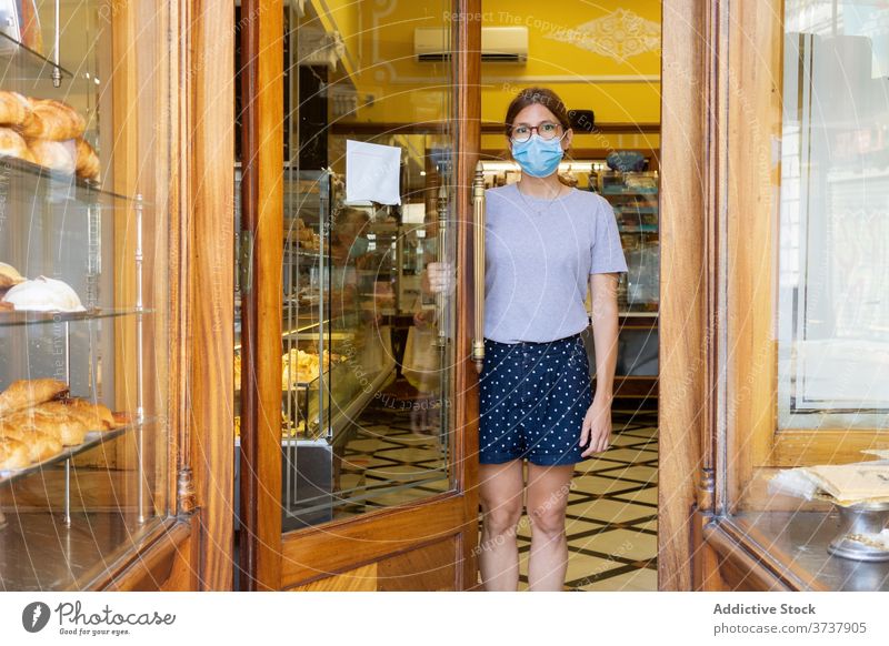 Frau mit Maske in der Bäckerei Verkäufer Innenbereich Tür Türöffnung Mundschutz medizinisch COVID gemütlich stehen neue Normale Sicherheit Personal behüten