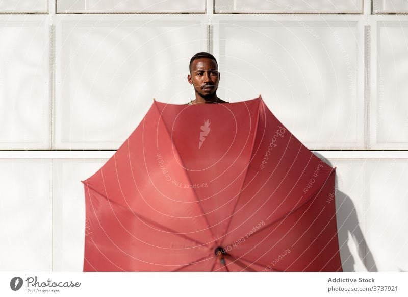 Afroamerikanischer Mann mit Regenschirm auf der Straße Deckung Tierhaut Sommer sonnig Großstadt urban Straßenbelag männlich ethnisch schwarz Afroamerikaner
