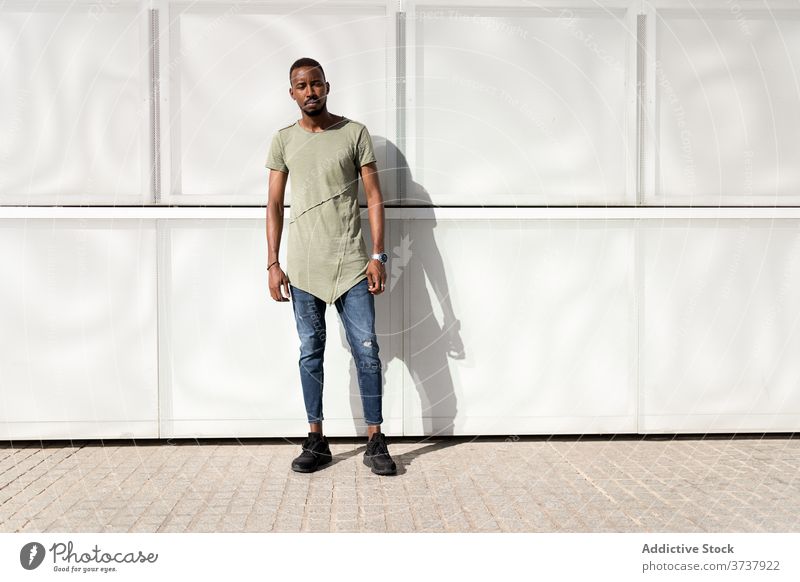 Ernster schwarzer Mann auf der Stadtstraße Großstadt urban Straße Gebäude Gelassenheit genießen Sonnenlicht modern Straßenbelag männlich ethnisch Afroamerikaner