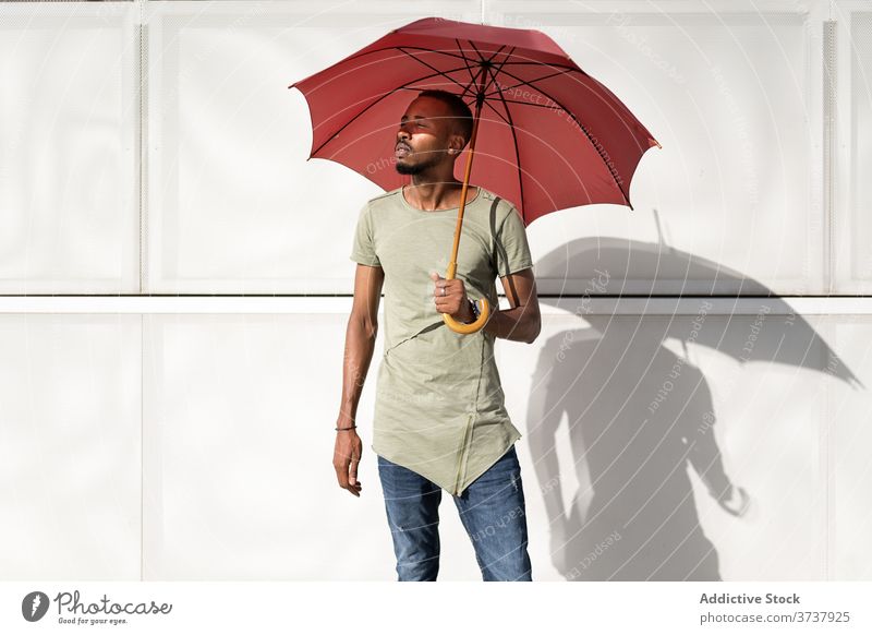 Ethnischer Mann an einem sonnigen Tag auf der Straße genießen Sommer Großstadt Regenschirm Tierhaut sich[Akk] entspannen Windstille Gelassenheit urban männlich