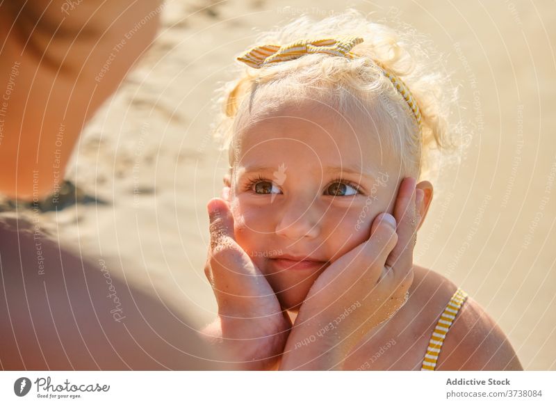 Hände um das Gesicht eines kleinen Mädchens mit einem Ausdruck der Bewunderung an einem Strand gewickelt Umarmen Bräune teilen reden Zusammengehörigkeitsgefühl