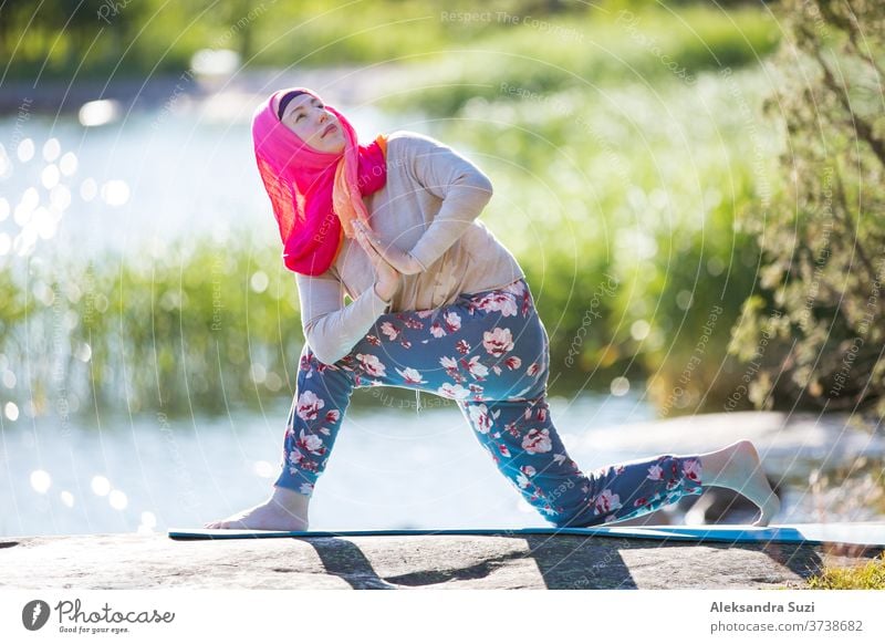 Attraktive Frau beim Hijab-Training im Park, meditierend. Sie macht Yoga-Übungen an der frischen Luft und genießt den frühen Morgen. Gesunder Lebensstil