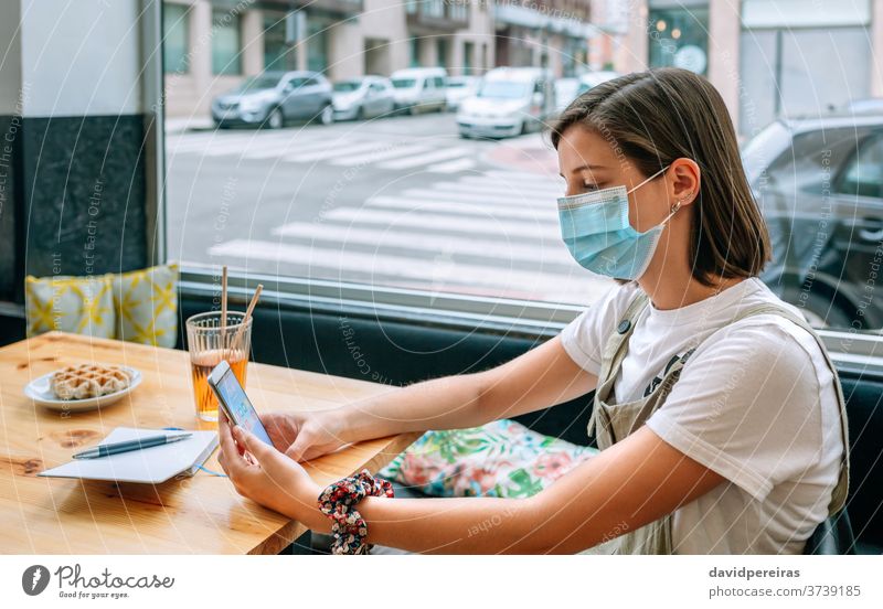 Frau mit Maske bei einem Imbiss in einem Café covid-19 Coronavirus Schutzmaske neue Normale Snack Frühstück Mobile Kaffeehaus Kantine Operationsmaske Mädchen