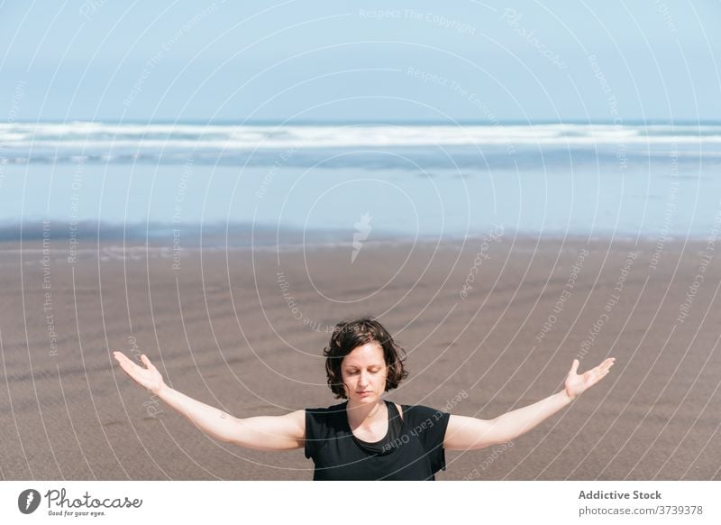 Schlanke Frau beim Meditieren am Strand Yoga MEER üben Asana Pose Augen geschlossen sitzen Gleichgewicht Windstille Meeresufer Harmonie Arme hochgezogen