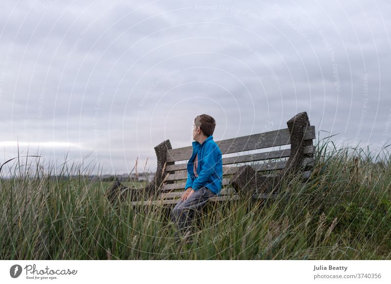 Junge auf einer Bank am Meer Seeküste MEER Meerblick wolkig Wolken Einsamkeit allein Gras Strandhafer Urlaub Pazifik Oregon Vereinigte Staaten Sommer cool