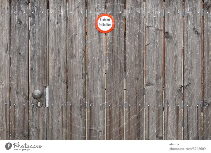 ein großes braunes Holztor mit einem kleinen Hinweisschild "Einfahrt freihalten" Tor Eingangstor Holtor Schild Schilder & Markierungen Schriftzeichen Schutz