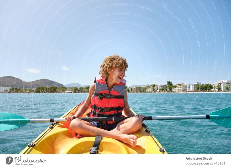 Junge mit Schwimmweste sitzt in einem Kajak im Meer sich[Akk] bewegen ernst müde sicher Wochenende freudig stoppen Reihe gefährlich Vergnügen Erholung Schutz