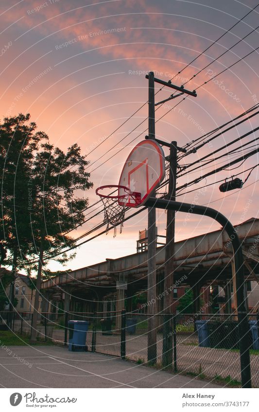 Basketballkorb für vor Zuggleisen bei Sonnenuntergang. Chicago Gericht Spielplatz urban Bahngleise Gasse Telefonleitungen