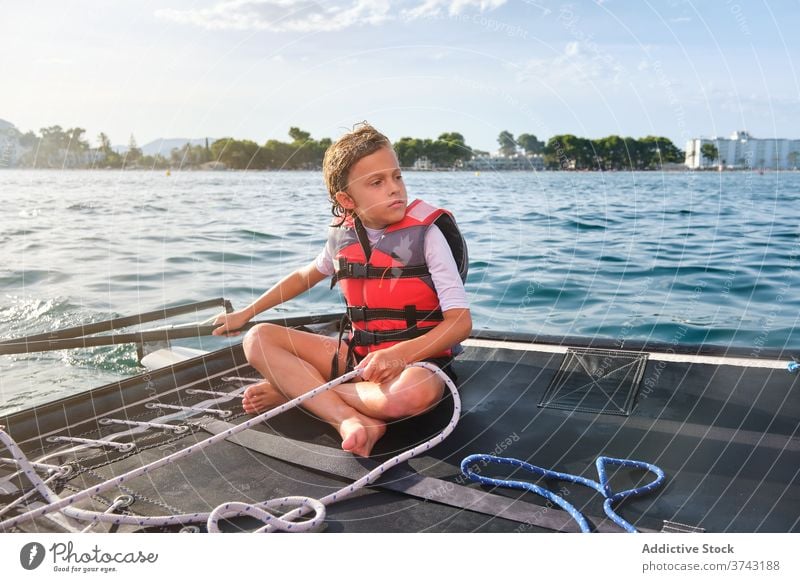 Ernstes Kind in Schwimmweste sitzt in einem Boot und hält das Ruder ernst Segelboot Abenteuer Segeln Ferien Meeresufer Jacht Yachting fahren ruder Sommer reisen