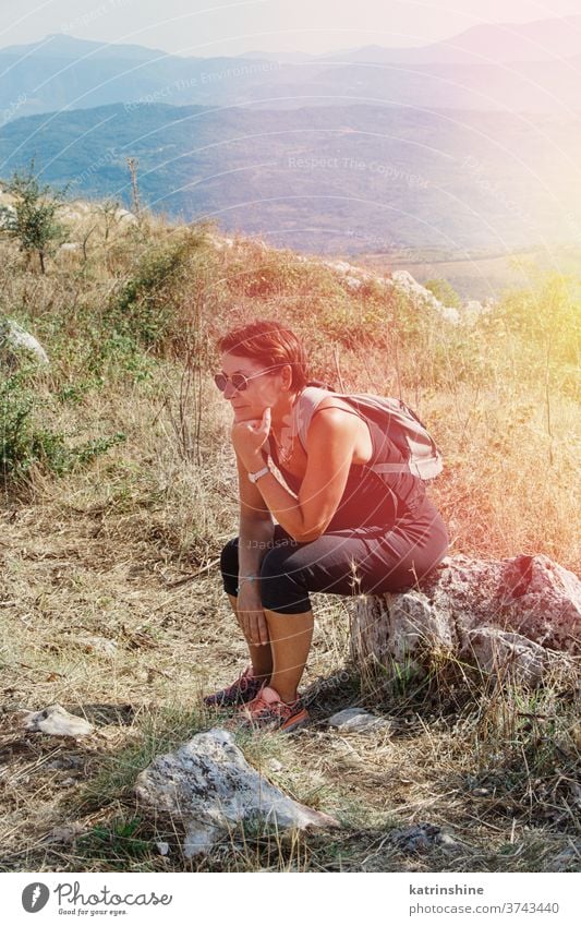 Wanderin legt an einem sonnigen Tag in den Bergen eine Pause ein Frauen wandern sitzen ruhen sich[Akk] entspannen Sport Natur im Freien acivity Erholung