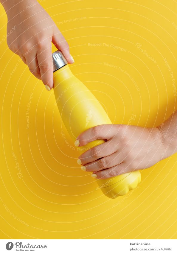 Nahaufnahme von Frauenhänden, die eine gelbe wiederverwendbare Stahlflasche auf gelbem Hintergrund halten Flasche Hand Monochrom ökologisch Wasser Thermo hell