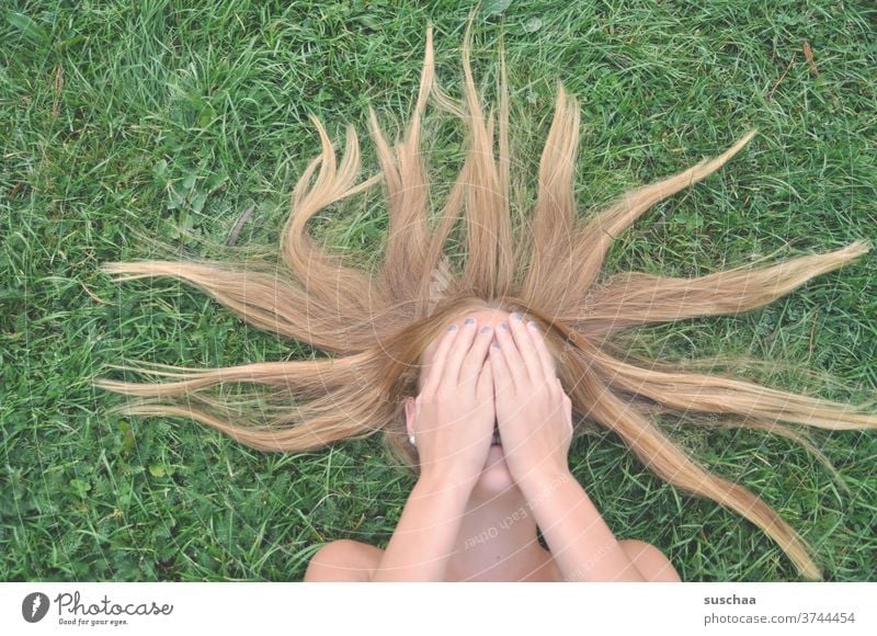 mädchen auf einem grünen rasen liegend mit händen vor dem gesicht Mädchen jung Jugend Pubertät Haare Rasen Hände Hände vorm Gesicht Jugendliche Haare & Frisuren
