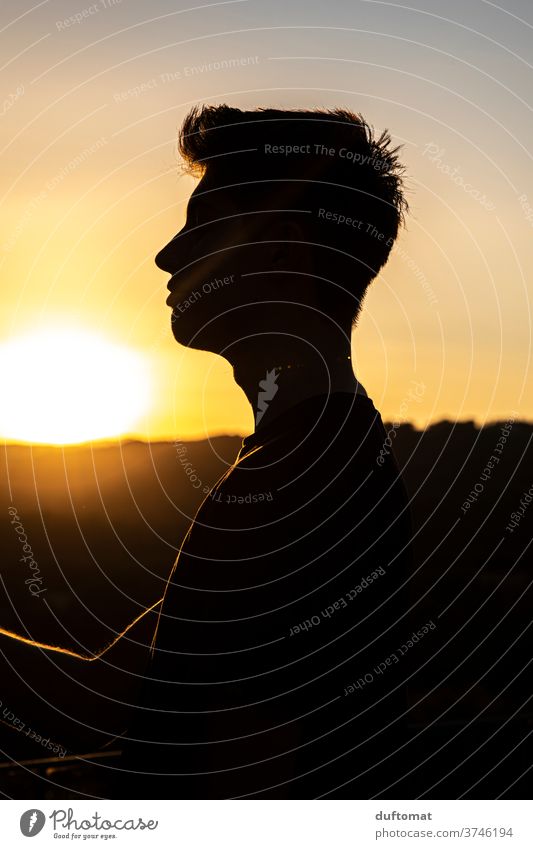 Teenager im Gegenlicht bei untergehender Sonne Italien Sonnenuntergang junger Mann männlich Silhouette Fernsicht Aussicht Porträt genießen Sonnenschein