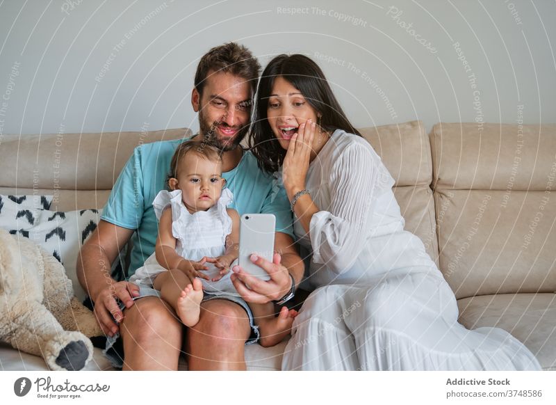 Paar mit einem Kleinkind auf dem Schoß macht ein Selfie mit dem Mobiltelefon Unschuld Erinnerungen Lebensstile Kindererziehung Eltern Elternschaft neugeboren