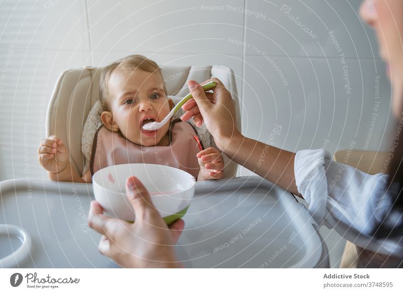 Anonyme Mutter, die ein Baby mit einem Lätzchen füttert Unschuld Teilen Säugling Mutterschaft Zusammengehörigkeitsgefühl Wohlbefinden Bonden Mund Kleinkind