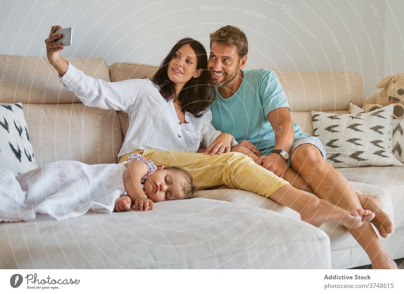Kleinkind schläft auf der Couch, während ein schwangeres Paar ein Selfie macht Verantwortung Erinnerungen Zärtlichkeit Einheit teilen Ruhe träumend Elternschaft