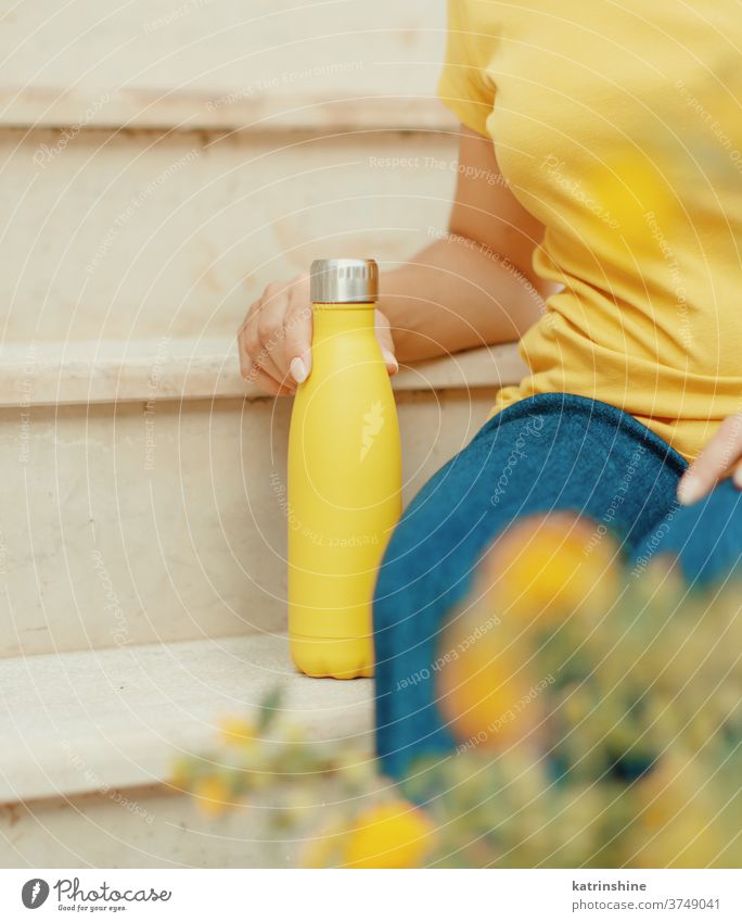 Junge Frau hält gelbe wiederverwendbare Flasche Hand gesichtslos abschließen Monochrom ökologisch Wasser Stahl Thermo Halt hell Attrappe Leichtmetall blanko