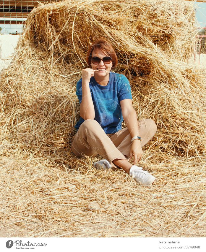 Junge Frau sitzt am Heuhaufen jung Mädchen lässig Heugarben sich[Akk] entspannen Kaukasier Stroh Ackerbau Sommer Ranch Lächeln Erwachsener ländlich Ernte