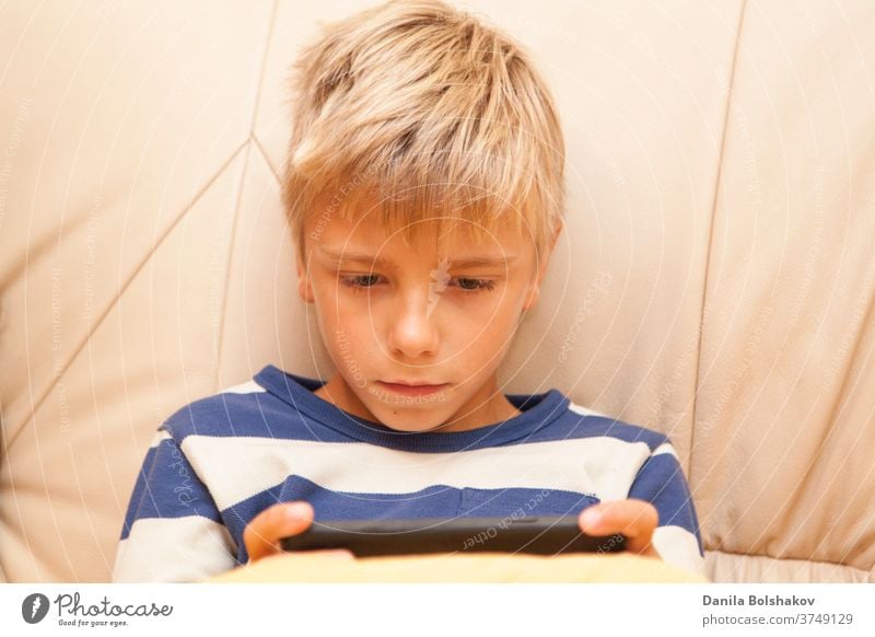 Kleines Kind spielt ein Spiel oder sieht sich etwas auf einem mobilen Smartphone an Cartoons Handy aussruhen Karikaturen anschauen Surfen im Netz Anschluss